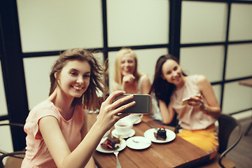 Image showing Two girl friends spend time together drinking coffee in the cafe, having breakfast and dessert.