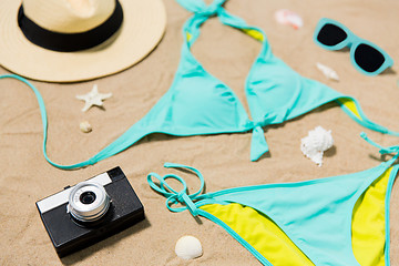 Image showing bikini, hat, camera and sunglasses on beach sand