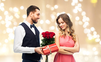 Image showing happy man giving woman flowers and present