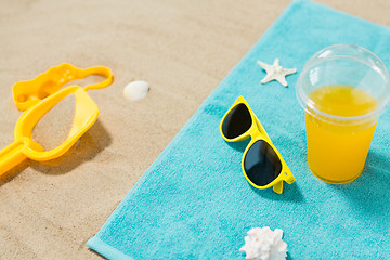 Image showing sunglasses, sand toys and juice on beach towel