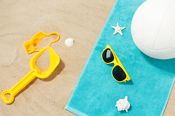 Image showing sunglasses, sand toys and ball on beach towel