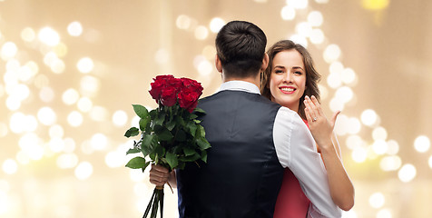 Image showing woman with engagement ring and roses hugging man