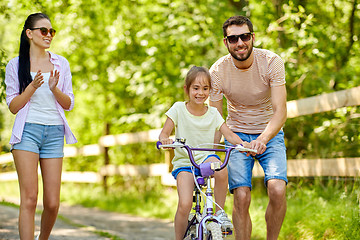 Image showing kid with patents learning to ride bicycle in park