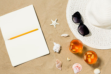 Image showing notebook, cocktails, hat and shades on beach sand