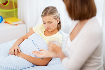 Image showing mother giving medicine to ill daughter at home