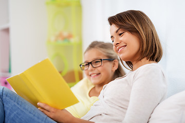 Image showing happy girl with mother reading book at home