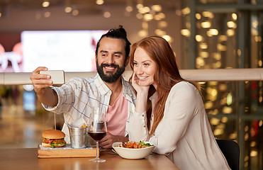 Image showing couple taking selfie by smartphone at restaurant