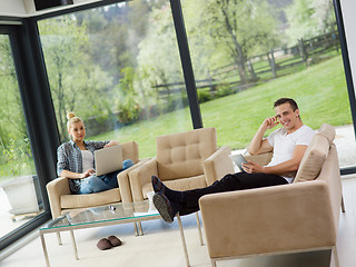 Image showing couple relaxing at  home with tablet and laptop computers