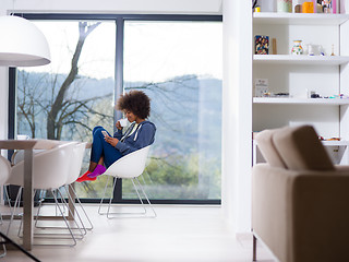 Image showing black woman drinking coffee and using a mobile phone  at home