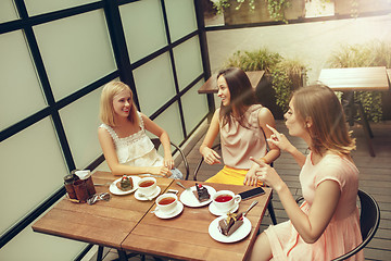 Image showing Two girl friends spend time together drinking coffee in the cafe, having breakfast and dessert.