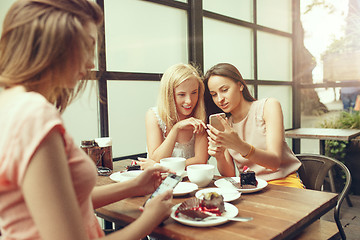 Image showing Two girl friends spend time together drinking coffee in the cafe, having breakfast and dessert.