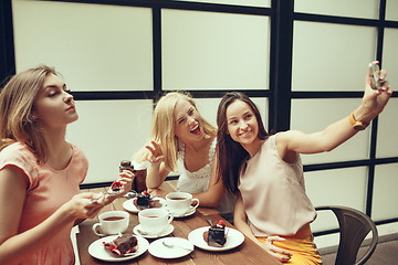 Image showing Two girl friends spend time together drinking coffee in the cafe, having breakfast and dessert.