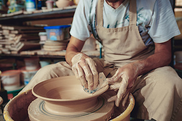 Image showing Creating a jar or vase of white clay close-up. Master crock. Man hands making clay jug macro.