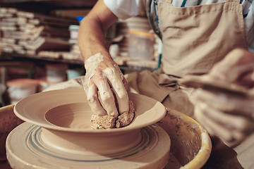 Image showing Creating a jar or vase of white clay close-up. Master crock. Man hands making clay jug macro.