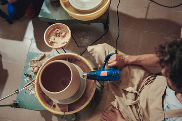 Image showing Creating a jar or vase of white clay close-up. Master crock. Man hands making clay jug macro.