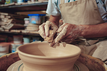 Image showing Creating a jar or vase of white clay close-up. Master crock. Man hands making clay jug macro.