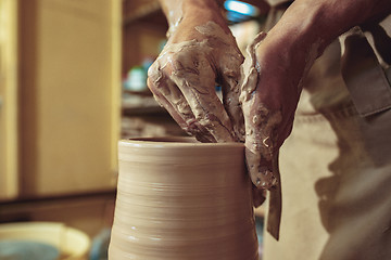 Image showing Creating a jar or vase of white clay close-up. Master crock. Man hands making clay jug macro.