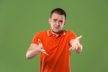 Image showing Beautiful male half-length portrait isolated on green studio backgroud. The young emotional surprised man