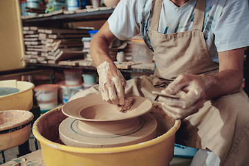 Image showing Creating a jar or vase of white clay close-up. Master crock. Man hands making clay jug macro.