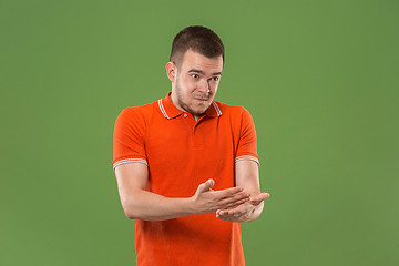 Image showing Beautiful male half-length portrait isolated on green studio backgroud. The young emotional surprised man