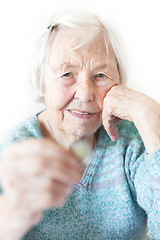 Image showing Cheerful elderly 96 years old woman sitting at table at home happy with a coin in her hand. Saving for retirement and financial planing concept