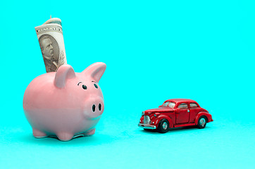 Image showing Pink piggy bank with a car on the table. Tinted. Concept of saving finances and contributions to property.
