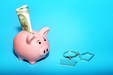 Image showing Pink piggy bank with a house on the table. Tinted. Concept of saving finances and real estate deposits.