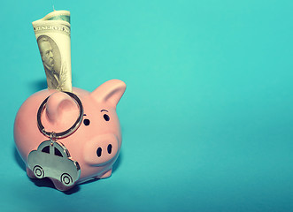 Image showing Pink piggy bank with a car on the table. Tinted. Concept of saving finances and contributions to property.