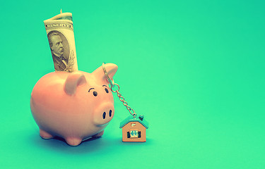 Image showing Pink piggy bank with a house on the table. Tinted. Concept of saving finances and real estate deposits.