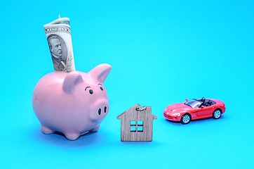 Image showing Pink piggy piggy bank with a house and a car on the table. Tinted. Concept of saving finances and real estate deposits.