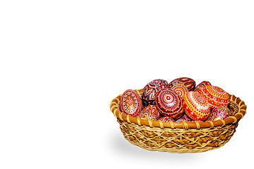 Image showing Wooden Easter eggs in a wicker basket, hand-painted with acrylic paints, isolated on a white background.