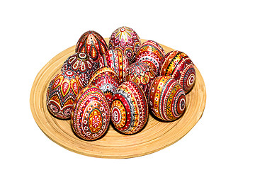 Image showing Wooden Easter eggs on a wooden plate, painted with patterns, hand-painted with acrylic paints, isolated on a white background.