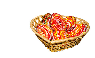 Image showing Wooden Easter eggs in a wicker basket, hand-painted with acrylic paints, isolated on a white background.