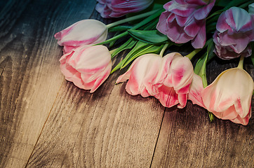 Image showing Bouquet of pink tulips on the background of old wooden boards with a place for the inscription, toned