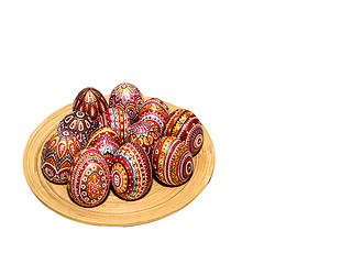 Image showing Wooden Easter eggs on a wooden plate, painted with patterns, hand-painted with acrylic paints, isolated on a white background.