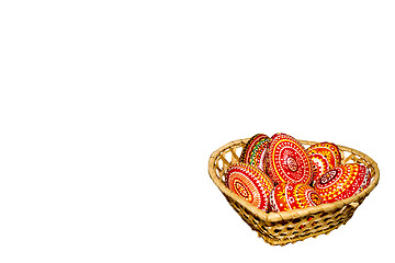 Image showing Wooden Easter eggs in a wicker basket, hand-painted with acrylic paints, isolated on a white background.