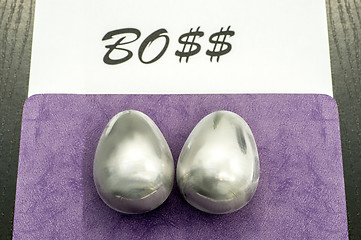 Image showing Two metal eggs on the office desk opposite the word Boss. The concept of power.