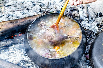 Image showing Soup is cooked in a tourist pot on the fire