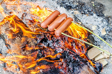 Image showing Grilling sausages over an open fire outdoors.