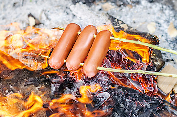 Image showing Grilling sausages over an open fire outdoors.