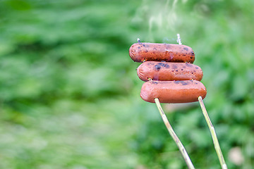 Image showing Grilling sausages over an open fire outdoors.