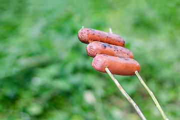 Image showing Grilling sausages over an open fire outdoors.