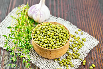 Image showing Mung beans in wooden bowl with thyme on dark board