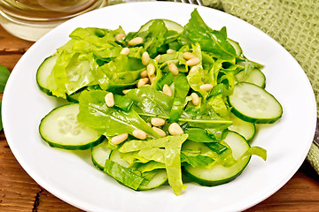 Image showing Salad from spinach and cucumber with napkin on wooden board