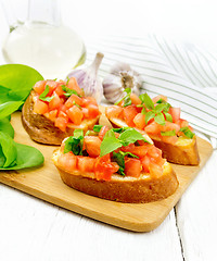 Image showing Bruschetta with tomato and spinach on light wooden table