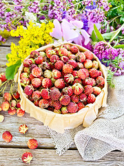 Image showing Strawberries in box with flowers on wooden board