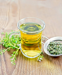 Image showing Tea of thyme in mug with strainer on old wooden board