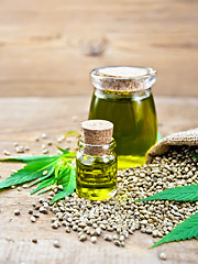 Image showing Oil hemp in two jars with grain on old board