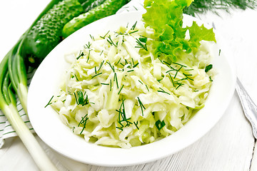 Image showing Salad of cabbage and cucumber in plate on light board