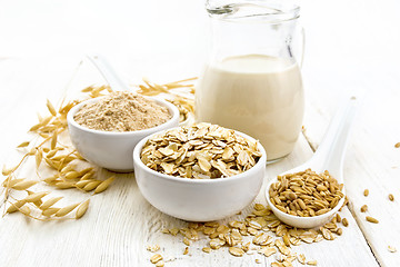 Image showing Oat flakes with flour and milk on wooden board